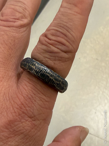 The finished ring on my finger. It has shiny bronze highlights and deep black recesses
